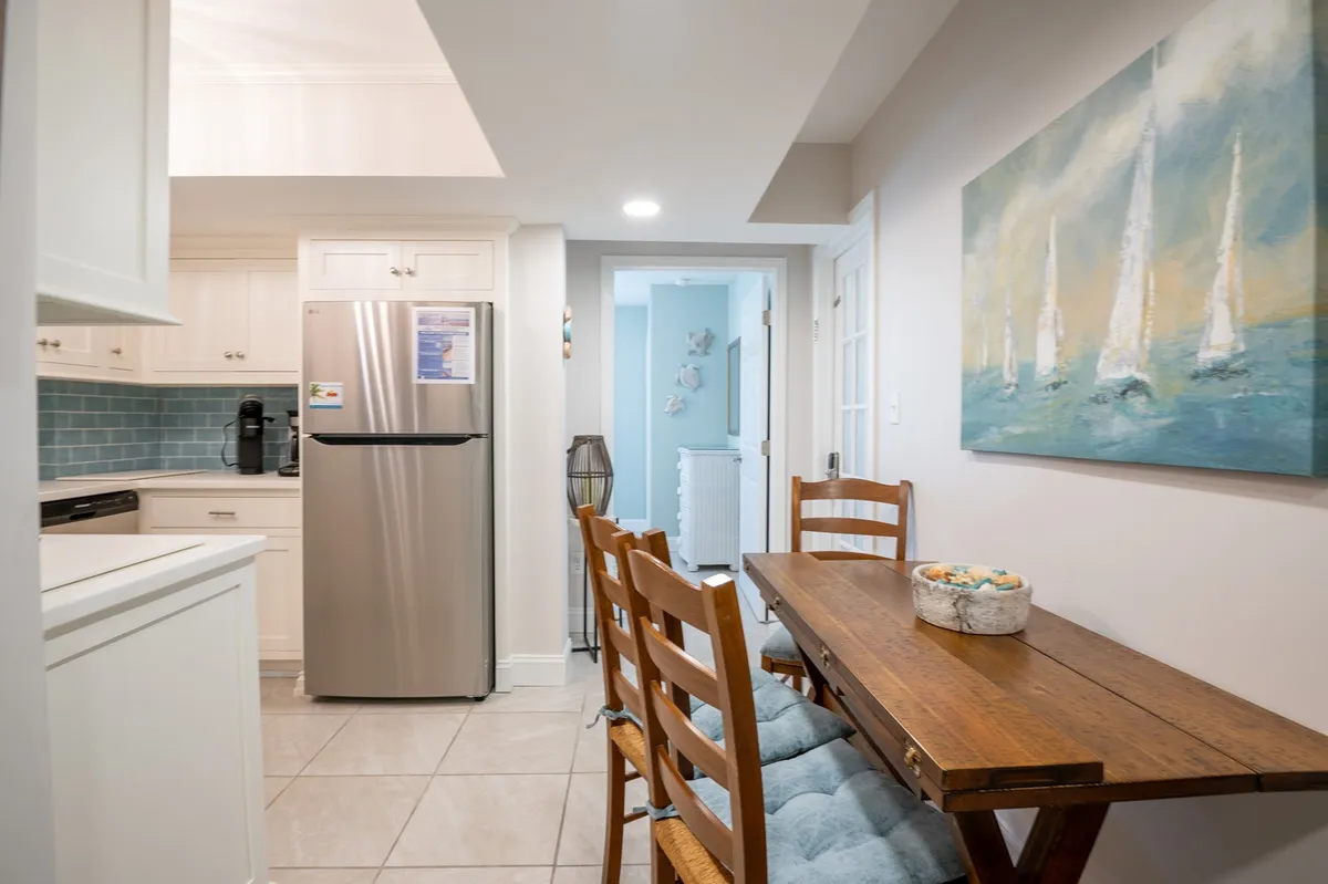 A bright and inviting dining area with a kitchen table, full-size fridge, and colorful painted artwork on the wall. The setting is ideal for family meals, casual breakfasts, or quiet moments with coffee, in a warm and functional environment.
